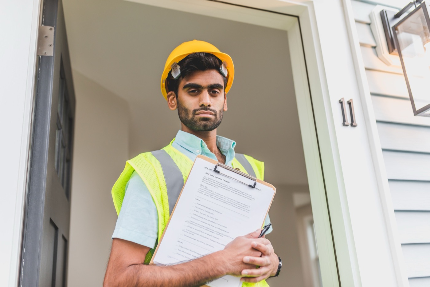 Technician reviewing an inspection checklist at a customer's front door