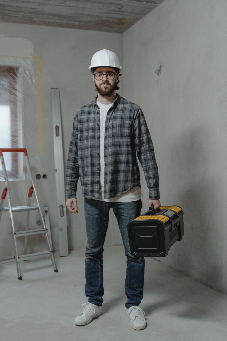 Plumber standing with a toolbox in an unfinished bathroom