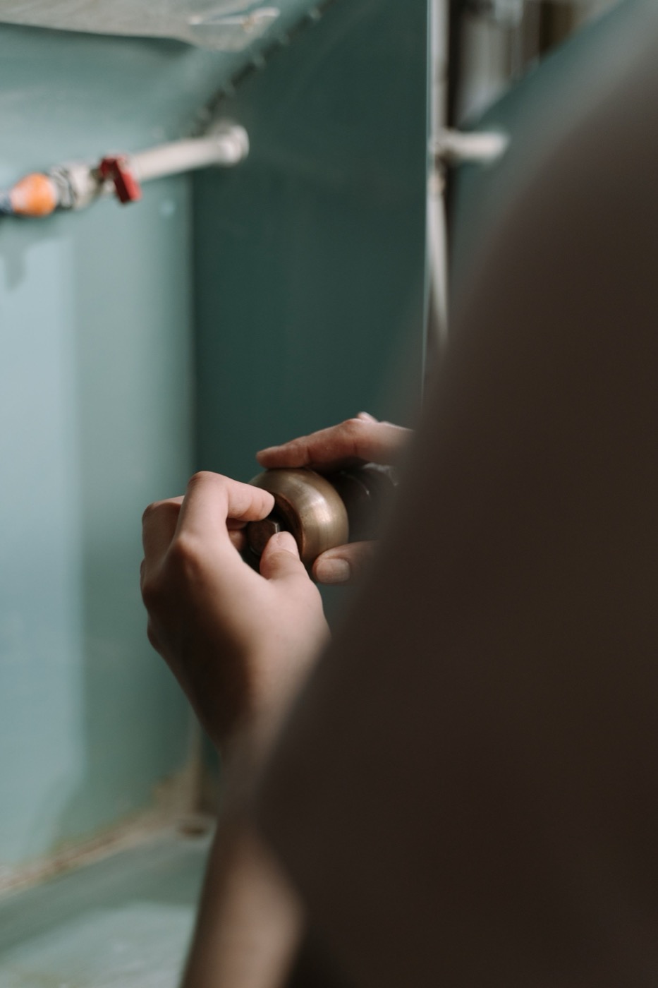 Plumber's hands tightening a supply line valve